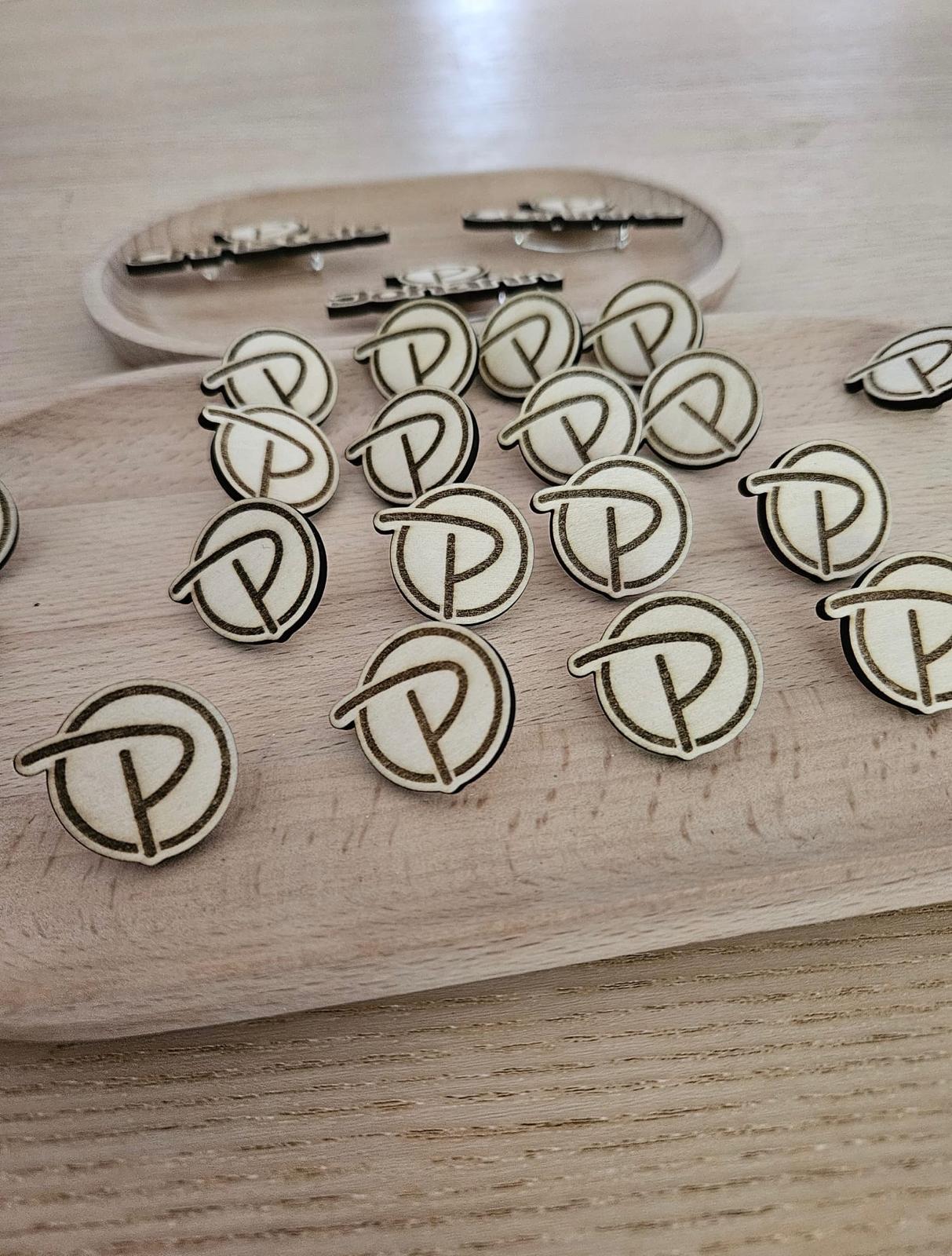 Badges en bois découpés et gravés, présentés sur un plateau en bois