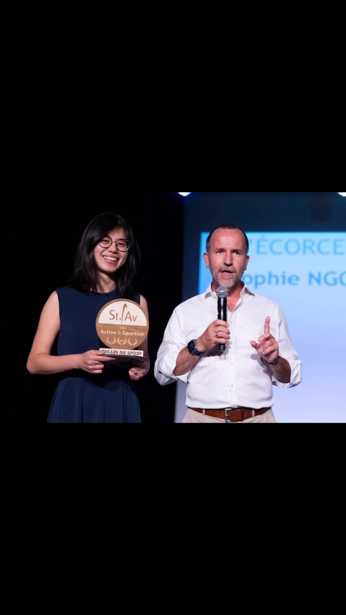 Sophie présente un trophée en bois personnalisé lors d’un événement